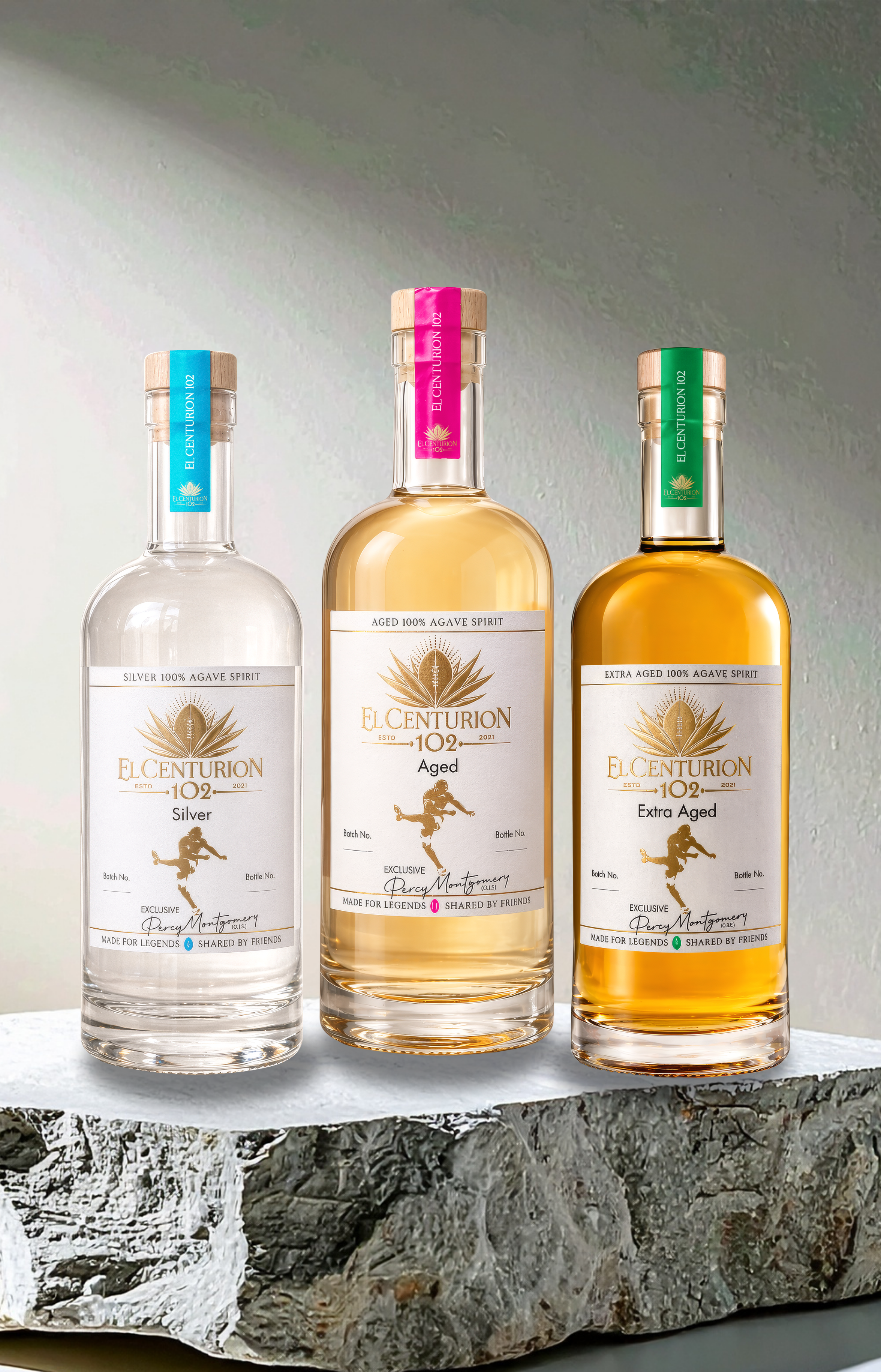 Three bottles of El Centurion 102 on a stone surface with a gray background