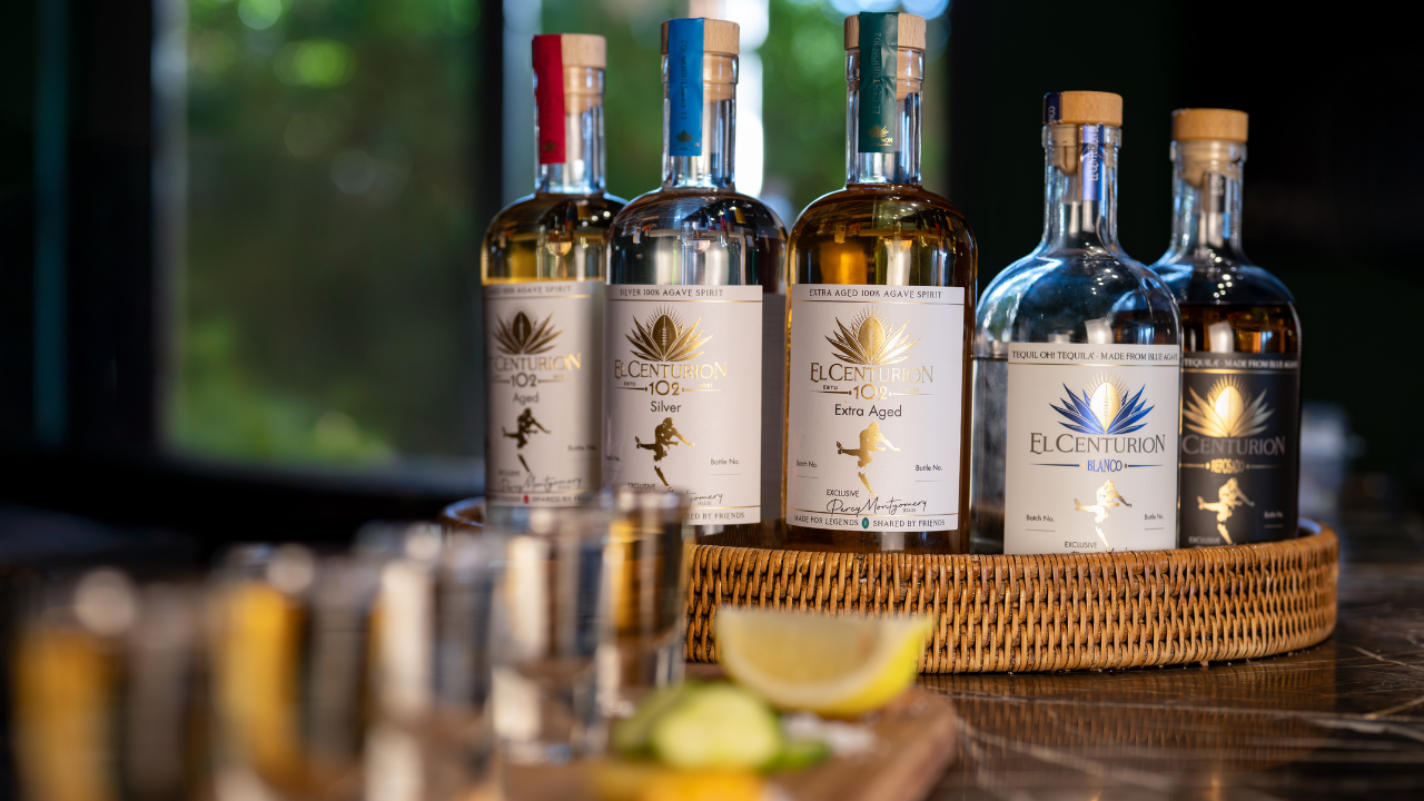 Five bottles of El Centurion 102 Agave Spirit on a wooden tray with a blurred background