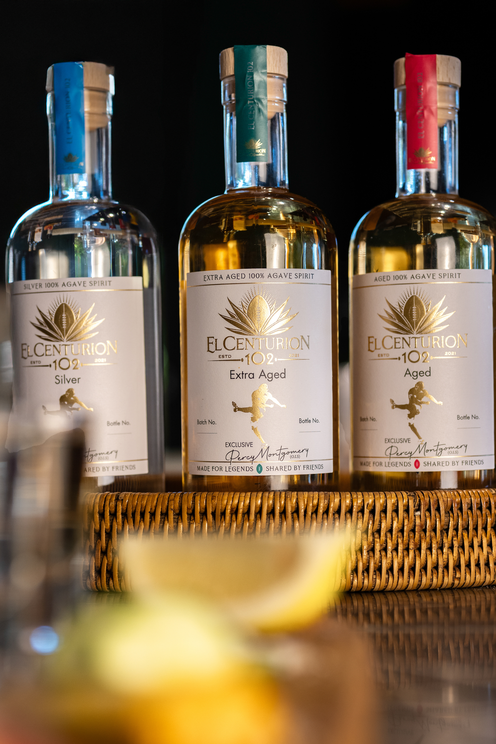 Three bottles of El Centurion agave on a bar tray with a blurred background