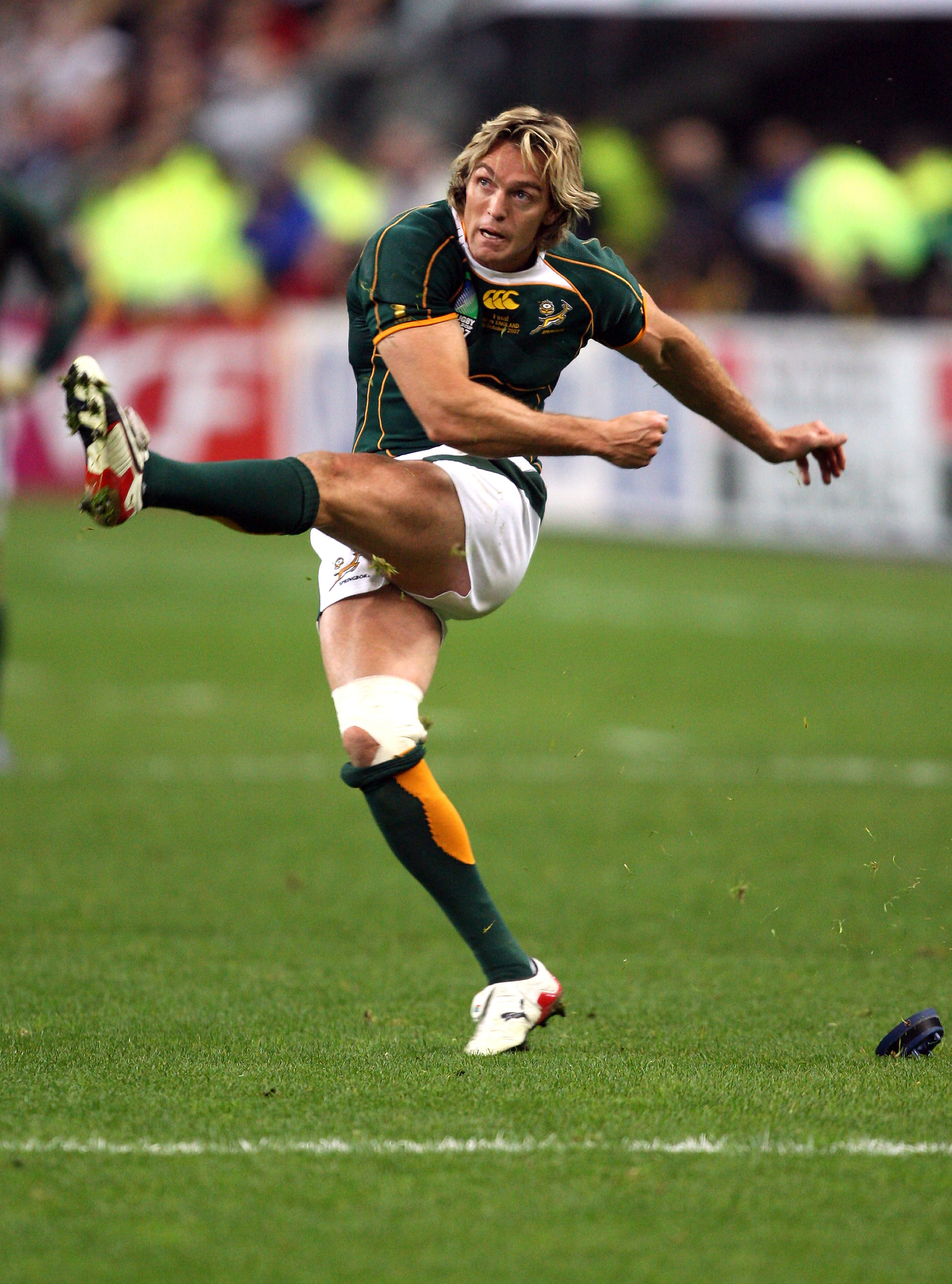 Rugby player in action on a grass field with spectators in the background